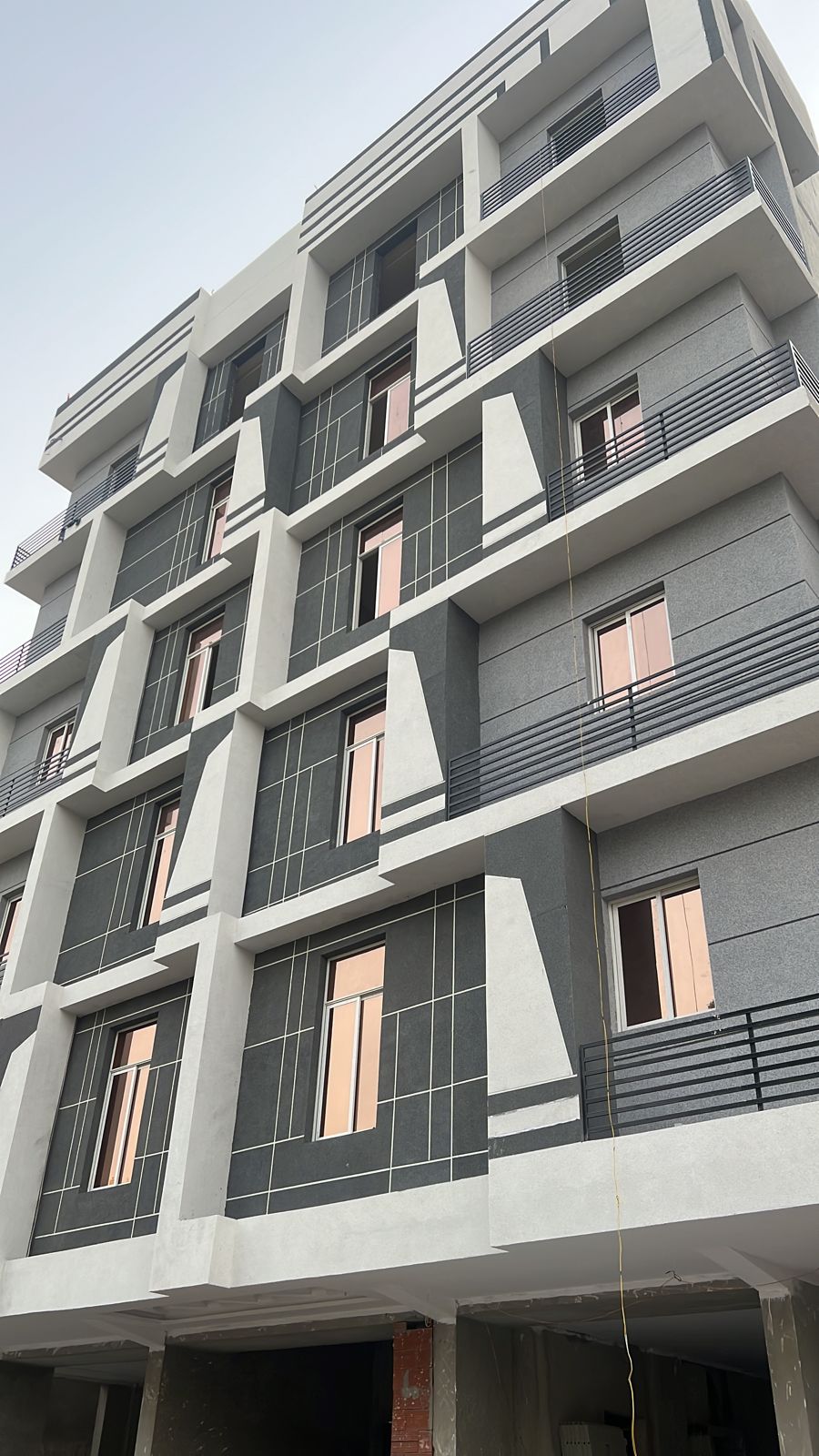 العزيزية - واجهة العمارة السكنية بألواح رمادية داكنة وبيضاء وشرفات بدرابزين أفقي - حي العزيزية جدة